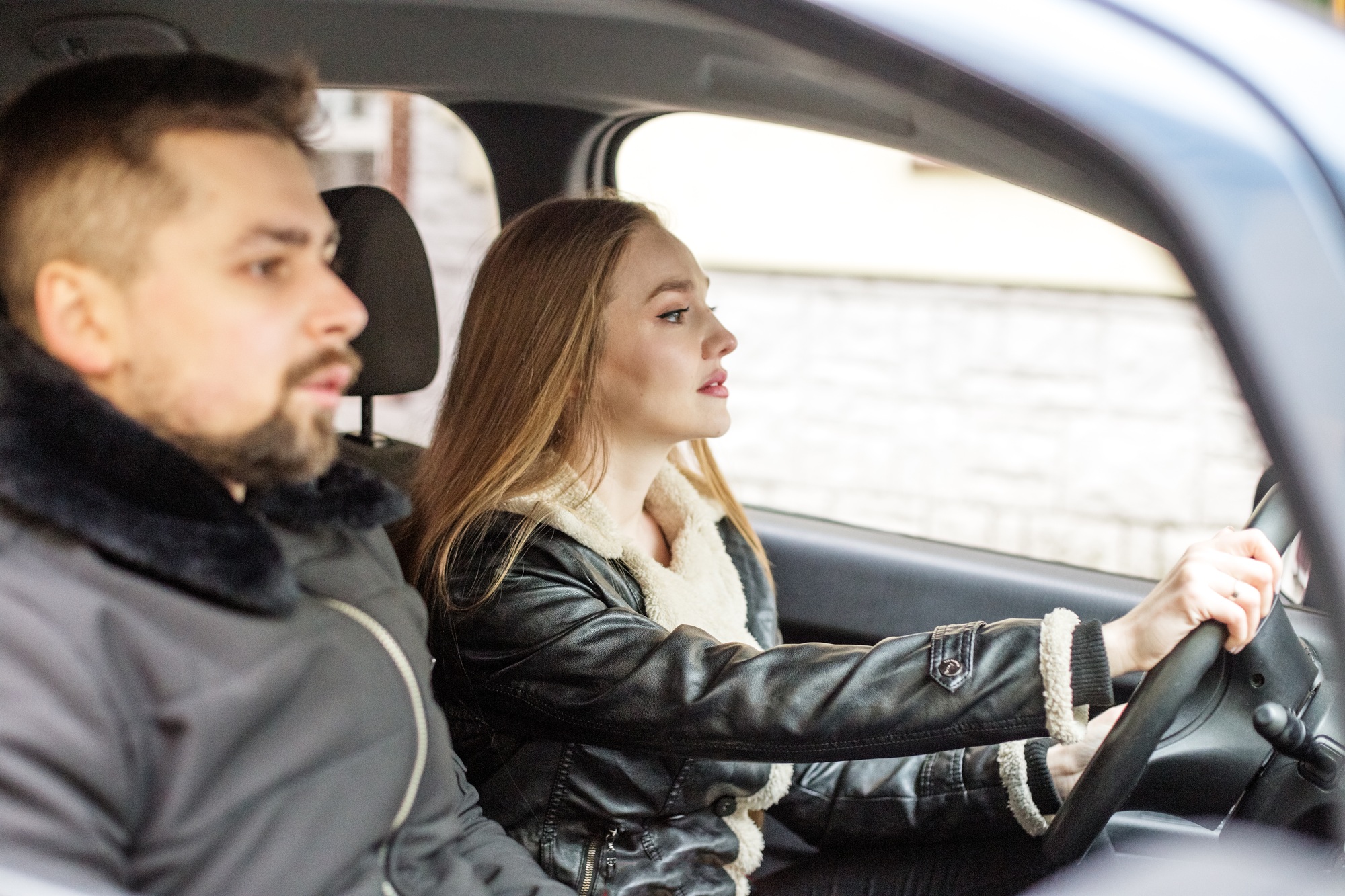 A girl and a man are sitting in a black car, a girl is driving, a good driver, learning to drive.